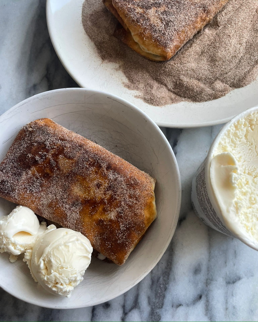 Burrito covered in cinnamon sugar in a bowl with ice cream